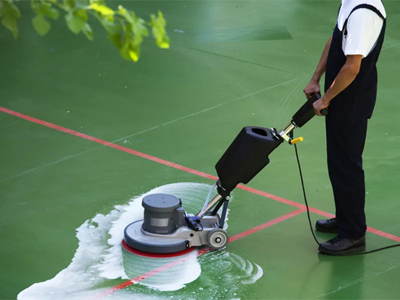Professional machine cleaning a synthetic tennis court surface