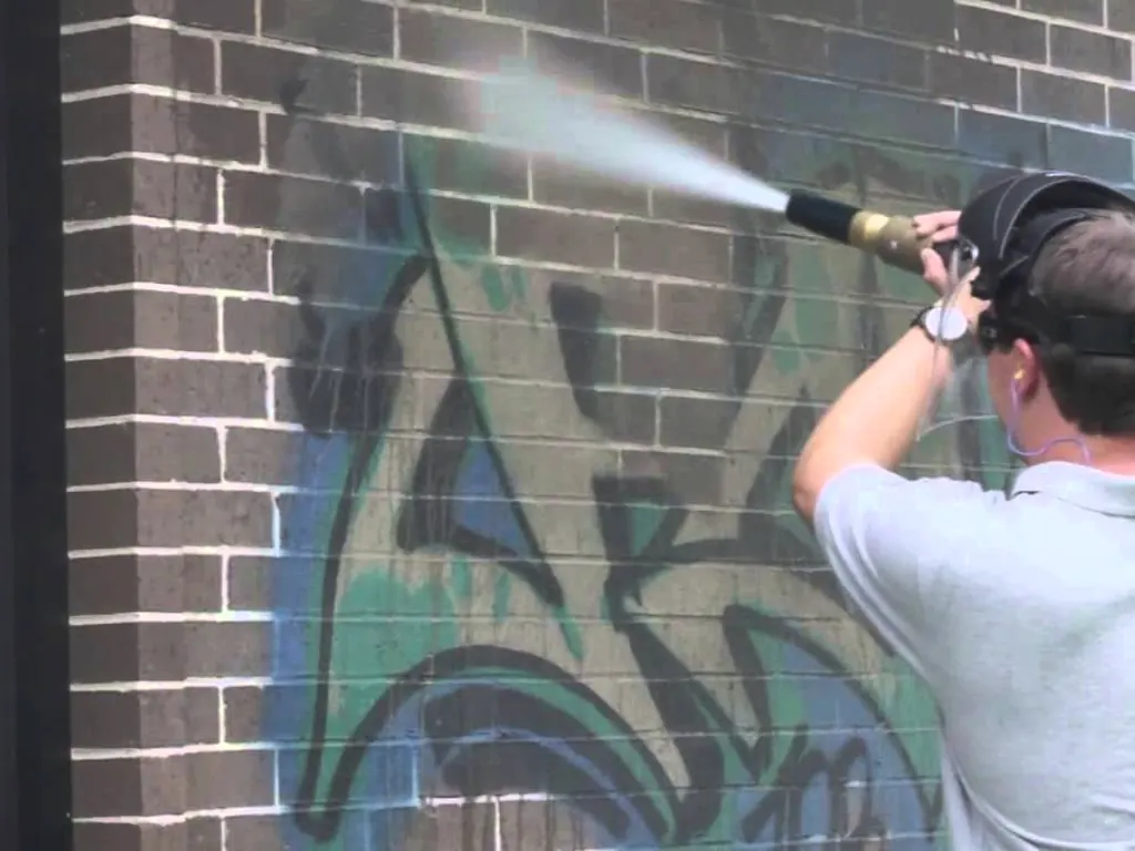 Graffiti being removed from a brick wall